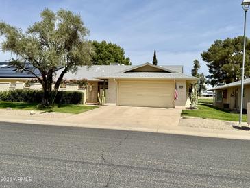 Charming single-story home featuring a well-manicured lawn and an inviting two-car garage at 12702 W Ashwood Dr, Sun City West, AZ 85375