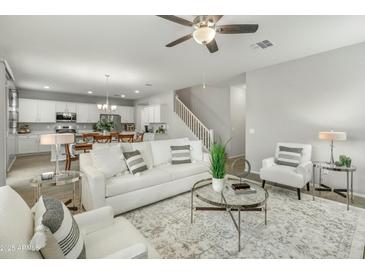Bright living room boasts a ceiling fan, modern furniture, and blends seamlessly into the dining area at 17176 W Molly Ln, Surprise, AZ 85387