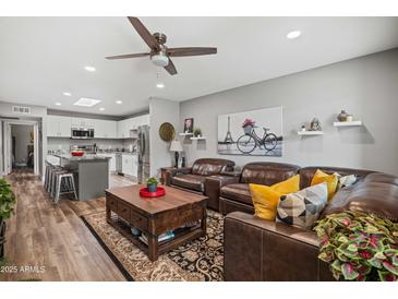 Inviting living room featuring a ceiling fan, plush leather seating, and stylish decor, perfect for relaxation and entertaining at 1951 N 64Th St # 69, Mesa, AZ 85205