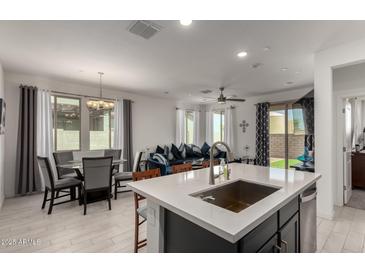 This kitchen features stainless appliances, gray cabinets, white countertops and an island with seating facing the dining area at 5383 N 205Th Dr, Buckeye, AZ 85396