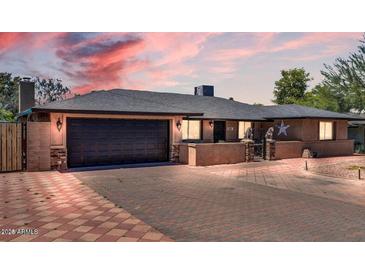 Charming single-story home with a well-manicured lawn, brick driveway, and attached two-car garage at 10602 N 35Th St, Phoenix, AZ 85028