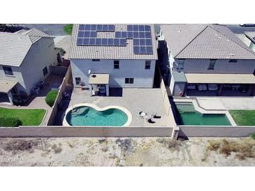 Aerial view of backyard features a kidney-shaped pool, patio, and solar panels atop a two-story home at 19061 N Toya St, Maricopa, AZ 85138