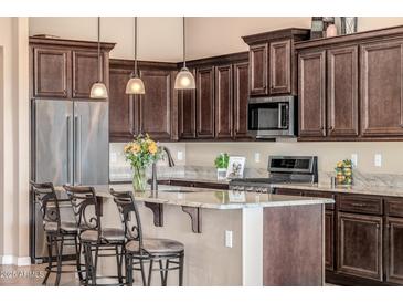 Well-lit kitchen features a large island with barstool seating, stainless steel appliances, and abundant cabinetry at 2124 N 89Th Pl, Mesa, AZ 85207