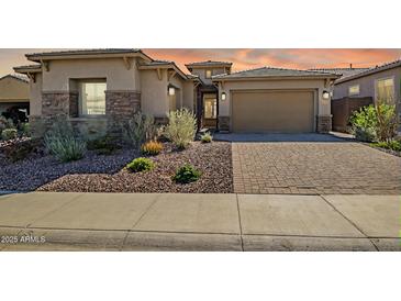 Beautiful single-story home showcasing desert landscaping, a paver driveway, and a two-car garage at 32297 N 133Rd Ln, Peoria, AZ 85383