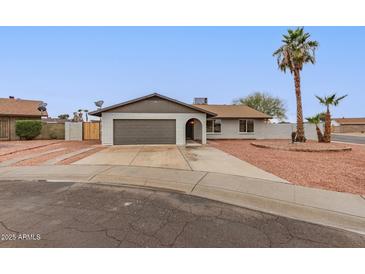 Charming single-story home with a spacious driveway, mature palm trees, and desert-friendly landscaping at 5561 W Greenbriar Dr, Glendale, AZ 85308