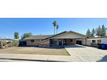 Charming brick single-story home featuring a carport, desert landscaping, and two mature palm trees at 623 N Parsell --, Mesa, AZ 85203