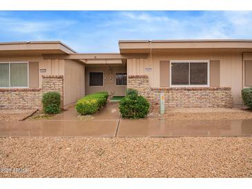 Charming single-story home with landscaped front yard and brick accents and green shrubbery at 14024 N Palm Ridge Dr, Sun City, AZ 85351