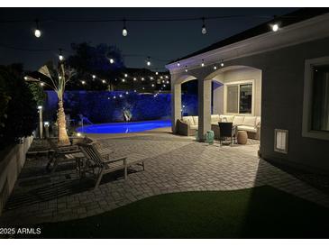 Cozy backyard with a private pool, patio area, and lounge chairs for relaxation beneath decorative string lights at 21359 E Camacho Rd, Queen Creek, AZ 85142