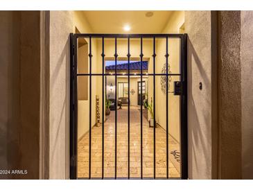 Welcoming courtyard featuring a secure wrought iron gate, beautiful brick pavers, and desert landscaping at 4376 S Santiago Way, Chandler, AZ 85248