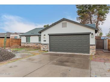 Charming single-Gathering home featuring a two-car garage and stone veneer accents, set against a blue sky at 6812 S 41St Pl, Phoenix, AZ 85042