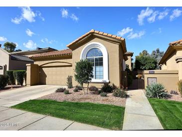 Charming home featuring a tile roof, arched window, well-manicured landscaping, and attached two car garage at 10960 N 78 St, Scottsdale, AZ 85260