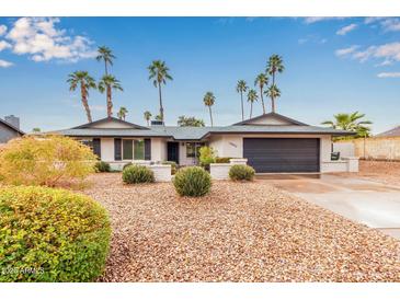 Charming ranch-style home with desert landscaping and a two-car garage, complemented by mature palm trees at 14042 N 44Th St, Phoenix, AZ 85032