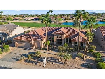 Beautiful single-story home with desert landscaping, a tile roof, a three-car garage, and palm trees at 16253 W Windcrest Dr, Surprise, AZ 85374