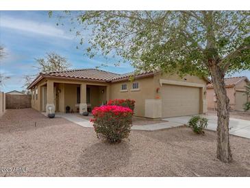 Charming single-story home featuring desert landscaping, a two-car garage and vibrant blooming shrubs at 25067 W Dove Trl, Buckeye, AZ 85326