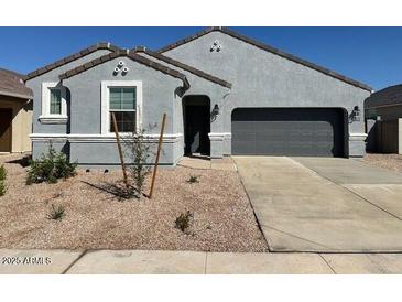 Charming single-story home features a gray exterior, low maintenance landscaping, and an attached two-car garage at 38150 W Bello Ln, Maricopa, AZ 85138