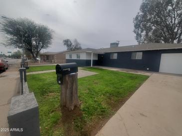 Charming single-story home features a well-maintained front yard with lush green grass and mature trees at 4114 N 55Th Ave, Phoenix, AZ 85031