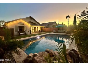 Inviting backyard pool with rock features and a view of the home at sunset at 4210 E Rosemonte Dr, Phoenix, AZ 85050