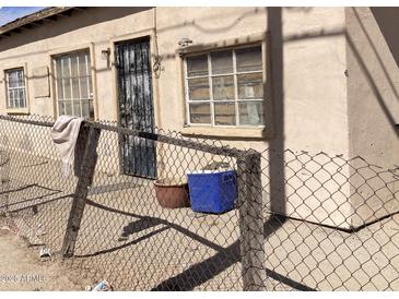 Shows the front of a tan house with a security door and chain-link fence at 5522 E Calle San Angelo St, Guadalupe, AZ 85283