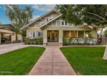 Charming home featuring a well-manicured lawn, lush landscaping, and a welcoming walkway to the front door at 102 W Almeria Rd, Phoenix, AZ 85003