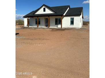 Charming single-story home featuring a white exterior, a dark roof, and a covered porch with wooden columns at 28003 N Faded Creek Dr, Florence, AZ 85132