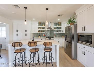 Bright kitchen with island seating, stainless appliances, and stylish backsplash at 3015 E Dahlia Dr, Phoenix, AZ 85032