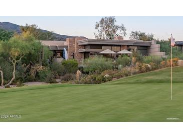 View of the rear exterior of the home with a golf course and desert landscaping at 40478 N 108Th Pl, Scottsdale, AZ 85262