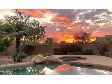 Gorgeous sunset reflecting in the pool water surrounded by lush landscaping at 12083 E Wethersfield Dr, Scottsdale, AZ 85259