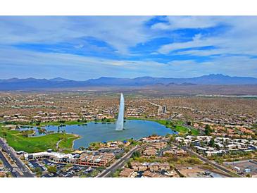 Stunning aerial view of the community with a lake, fountain, golf course, and picturesque mountain backdrop at 16807 E Gunsight Dr # B18, Fountain Hills, AZ 85268