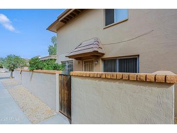 Tan two-story condo with a brick privacy wall and weathered wood gate offering a private entrance and patio at 17031 E Calle Del Oro -- # B, Fountain Hills, AZ 85268