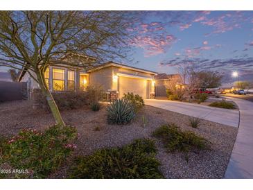 Charming single-story home featuring a well-maintained front yard and a two-car garage at sunset at 17796 W Sandy Rd, Goodyear, AZ 85338