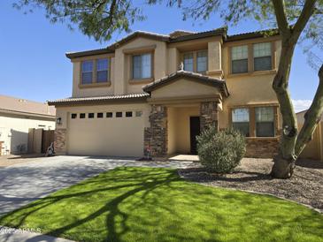 Two-story home featuring a two-car garage, manicured lawn, and a mix of stone and stucco finishes at 28273 N Castle Rock Dr, San Tan Valley, AZ 85143