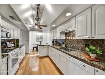 Bright kitchen featuring granite counters, white cabinets, stainless steel sink, and hardwood floors at 6310 E Avalon Dr, Scottsdale, AZ 85251