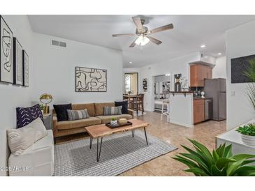 Inviting living room features tile floors, a ceiling fan and provides access to kitchen and dining room at 6900 E Princess Dr # 1228, Phoenix, AZ 85054