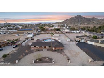 Expansive aerial view of a desert home with a pool, circular drive, and mountain backdrop in a private, fenced lot at 9120 W Villa Lindo Dr, Peoria, AZ 85383