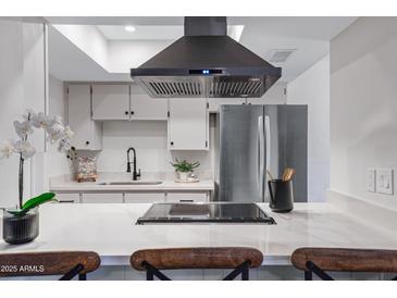 Modern kitchen featuring white cabinets, stainless steel appliances, and an island cooktop at 1455 N Alma School Rd # 38, Mesa, AZ 85201