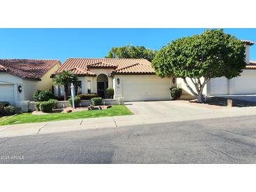 Charming single-story home with a tile roof, lush landscaping, and attached garage, ready for move-in at 5055 E Paseo Way, Phoenix, AZ 85044