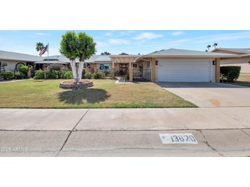 Charming home featuring a well-manicured lawn, mature trees, and an attached two-car garage, creating a welcoming curb appeal at 13620 N Hawthorn Dr, Sun City, AZ 85351