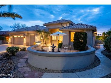 Charming exterior featuring a quaint patio with seating and desert landscaping at twilight at 17642 N Ironhorse Dr, Surprise, AZ 85374
