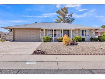 Charming single-story home featuring a well-manicured yard, neutral tones, and an attached two-car garage at 18402 N 94Th Dr, Sun City, AZ 85373