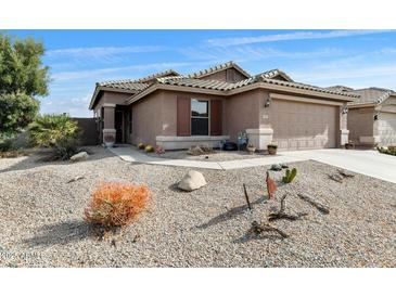 Single-story home with a two-car garage, low maintenance landscape, and neutral toned exterior paint at 43870 W Baker Dr, Maricopa, AZ 85138