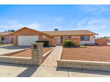 Charming single-story home with a two-car garage, landscaped yard, and inviting brick pathway at 5255 W Caribbean Ln, Glendale, AZ 85306