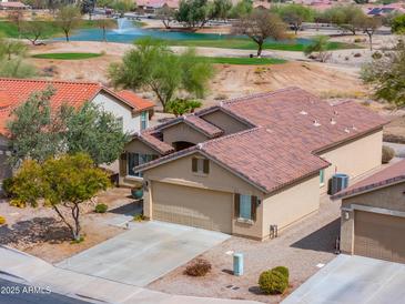 Beautiful single-Gathering home with desert landscaping, red tile roof, and attached two-car garage with golf course in the background at 188 N Nueva Ln, Casa Grande, AZ 85194
