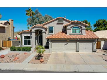 Charming two-story home featuring a red tile roof and a three-car garage, set against a clear blue sky at 19277 N 78Th Ln, Glendale, AZ 85308