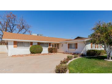 Charming single-story home with white brick and shutters, manicured lawn, and orange tree at 4510 W Keim Dr, Glendale, AZ 85301