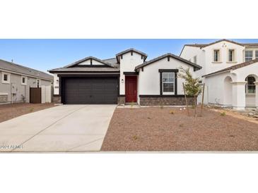 Inviting single-story home featuring a two-car garage, red door, and low maintenance desert landscaping at 7414 W Whitehorn Trl, Peoria, AZ 85383