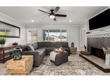 Bright living room with a corner fireplace, large gray sofa, and lots of natural light from the window at 8345 E Oak St, Scottsdale, AZ 85257