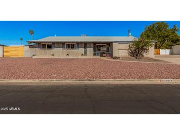 Charming single story home featuring a low maintenance desert rock yard and neutral brick facade at 1002 W Fairway Dr, Mesa, AZ 85201