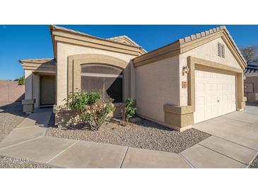 Beige single-story home featuring a two car garage, desert landscaping, and concrete walkway at 14717 N 130Th Ln, El Mirage, AZ 85335