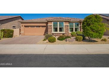 Charming single-story home featuring a two-car garage, stone accents, desert landscaping, and a tile roof at 18118 W Redwood Ln, Goodyear, AZ 85338