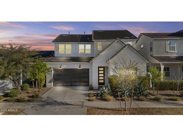 Charming two-story home featuring a modern garage door and well-manicured landscaping at 10150 E Thistle Ave, Mesa, AZ 85212